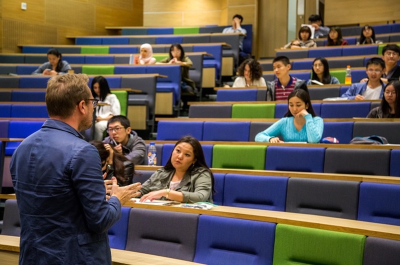 Medium pre sessional english students and teacher in a lecture theatre